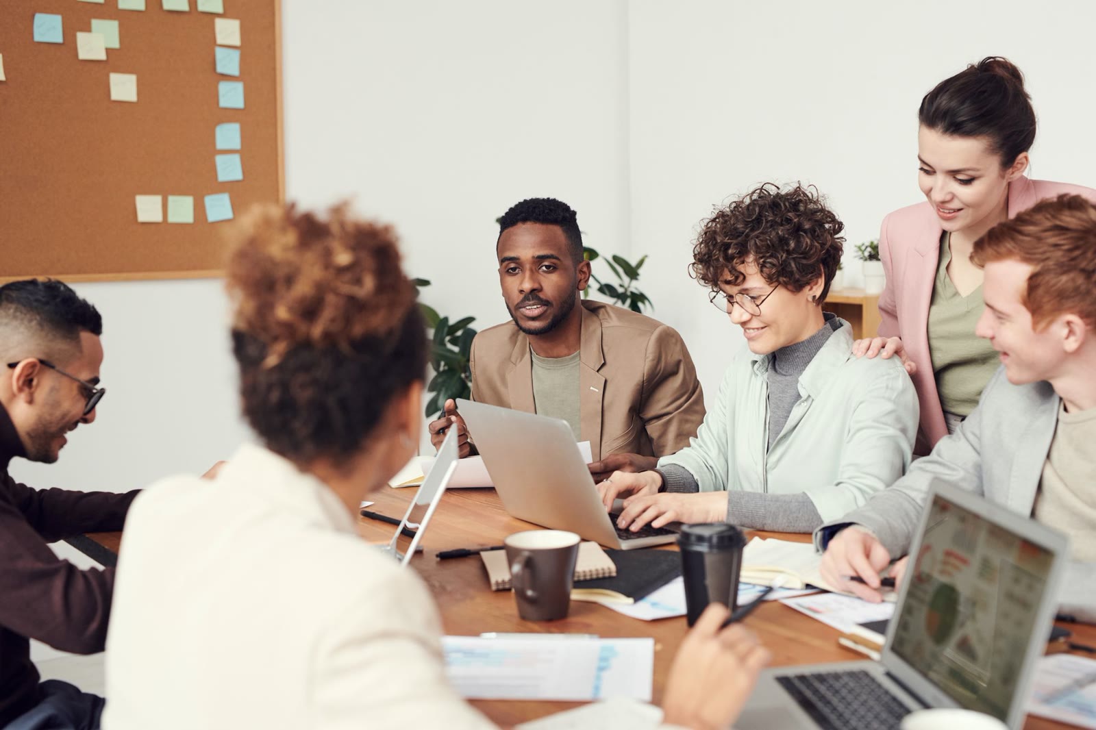 Professionals meeting around a conference table, laptops open, talking through a project together.